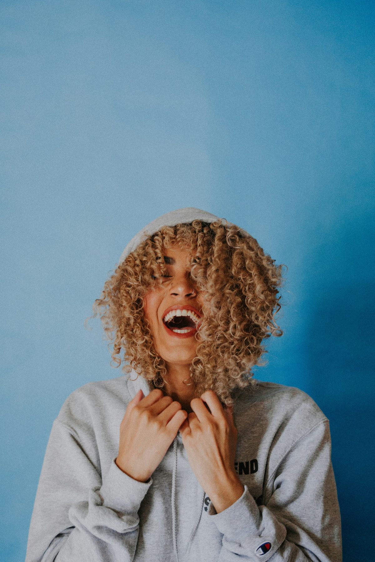Woman with curly hair laughing, showing a bright smile